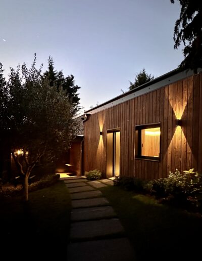 Façade en bois de la Salle de Sport. Photo de nuit. La façade est éclairée.